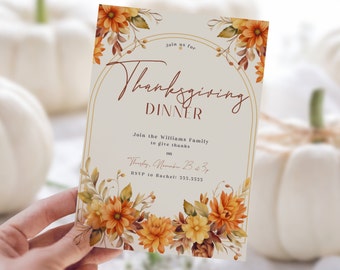 Könnte beinhalten: Einladung zum Thanksgiving-Dinner mit floralen Akzenten. Die Einladung zeigt den Text "Thanksgiving Dinner" in einer dekorativen Schriftart, mit Details zur Veranstaltung. Das Design umfasst orange und gelbe Blumen und Blätter auf cremefarbenem Hintergrund.