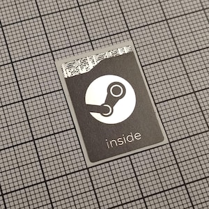 Pode incluir: Um autocolante retangular com fundo cinzento e logótipo Steam branco. A palavra "inside" está impressa em branco abaixo do logótipo. O autocolante está sobre um fundo de grelha cinzenta.
