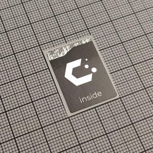 Pode incluir: Um autocolante retangular a preto e branco com a palavra "inside" impressa. O autocolante apresenta um design geométrico branco e um código de barras no topo. O autocolante está colocado sobre um fundo de grelha cinzenta.