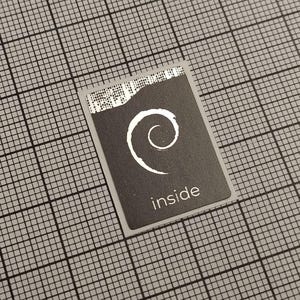 May include: A rectangular black card with a white swirl design and the word "inside" printed in white. The card has a torn edge at the top and is set against a grid background.