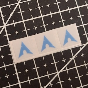 May include: Three square stickers arranged in a horizontal row, each featuring a light blue Arch Linux logo centered on a white background. The stickers are presented as a single strip, showcasing the iconic triangular emblem with a rounded cutout.