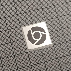 May include: A square sticker featuring the Chrome logo, a grey circle with a blue, yellow, and red segment. The sticker is on a white background with a grey grid pattern.