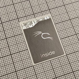 Könnte beinhalten: Eine rechteckige, dunkelgraue Karte mit dem weißen Aufdruck "inside". Die Karte zeigt ein weißes, stilisiertes Drachenlogo und ein Muster oben. Die Karte liegt vor einem Rasterhintergrund.