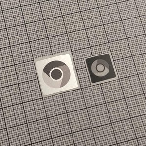 May include: Two square stickers with the Chrome logo, one larger and one smaller. The larger sticker has a silver border and a white background. The logo is a circle with segments of gray, yellow, and blue. The smaller sticker is black and gray.