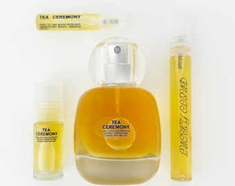Puede incluir: Una colección de productos de fragancia Tea Ceremony que incluye un frasco de perfume de vidrio redondeado, un pequeño vial roll-on y un tubo de spray delgado, todos con líquido dorado. Un vial de muestra pequeño tiene los ingredientes.
