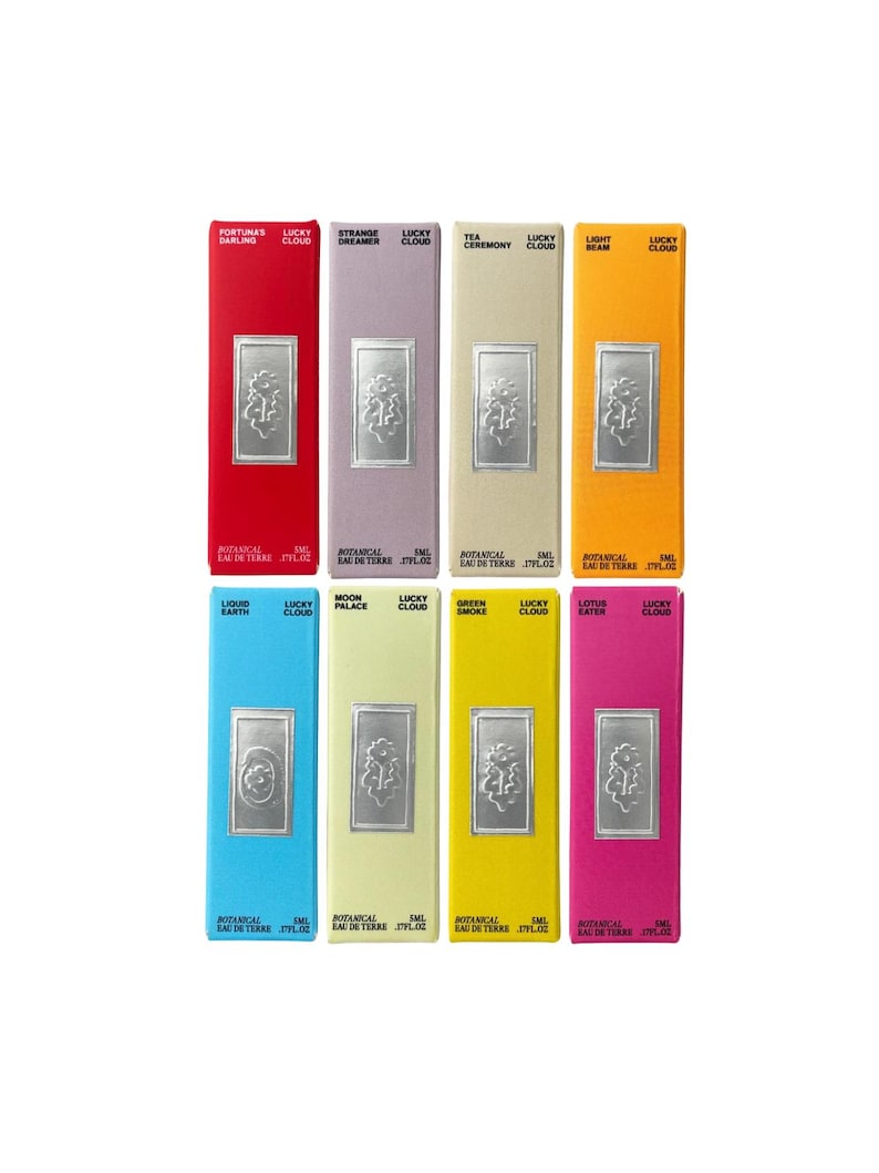 K&ouml;nnte beinhalten: Acht rechteckige Parf&uuml;mschachteln in Rot, Lavendel, Beige, Orange, Blau, Hellgr&uuml;n, Gelb und Pink. Jede Schachtel zeigt ein silbernes, gepr&auml;gtes Blumenemblem, den Text Lucky Cloud und spezifische Duftnamen wie Fortuna's Darling.