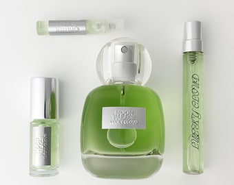 Könnte beinhalten: Ein Set aus drei Glasparfümflaschen mit hellgrüner Flüssigkeit. Die größte Flasche ist abgerundet und hat ein silbernes Etikett mit der Aufschrift Moon Palace Lucky Cloud. Zwei kleinere Sprühfläschchen tragen ebenfalls den Text.
