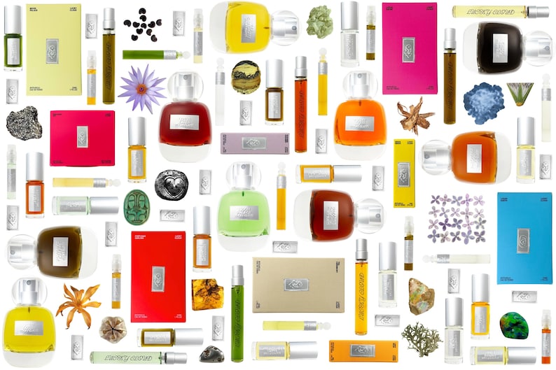 K&ouml;nnte beinhalten: Eine Sammlung verschiedener Parf&uuml;mflakons, rechteckiger Duftschachteln und kleiner Ampullen in verschiedenen Farben wie Rot, Gelb, Blau, Gr&uuml;n und Orange, durchsetzt mit kleinen nat&uuml;rlichen Elementen wie Steinen, getrockneten Blumen und Bl&auml;ttern.