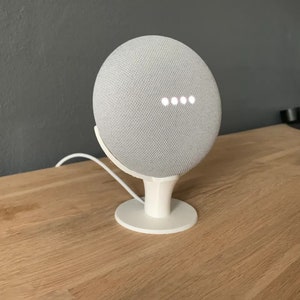 May include: A white smart speaker with a gray fabric exterior and a white stand. The speaker has a row of five white lights on the front.