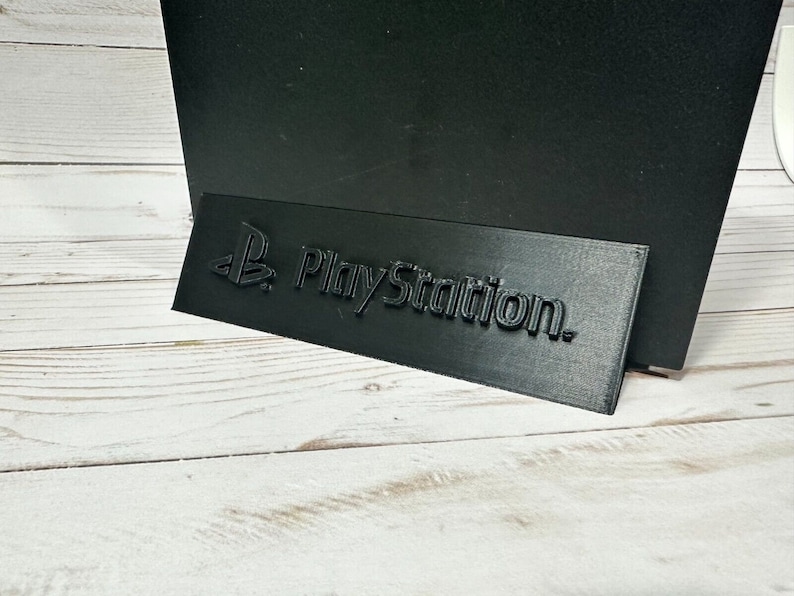 May include: A black plastic stand with the PlayStation logo embossed on it.