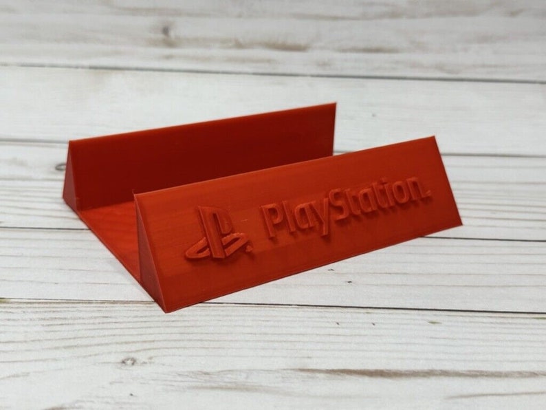 May include: A red plastic stand with the PlayStation logo and the word "PlayStation" printed on it.