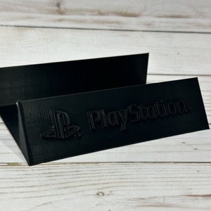 May include: Black plastic stand with the PlayStation logo and the words "PlayStation" printed on it.