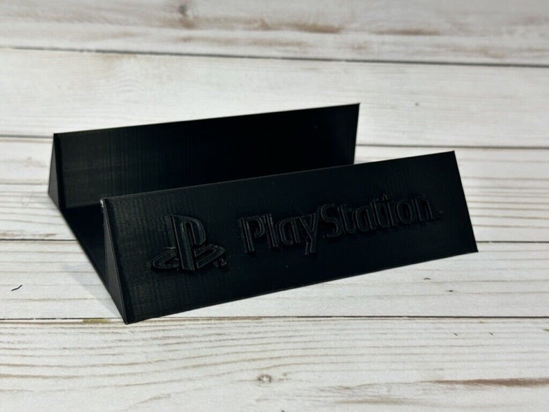 May include: Black plastic stand with the PlayStation logo and the words "PlayStation" printed on it.