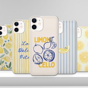 May include: A collection of five phone cases with various designs. One case features the text "LIMONCELLO" with lemon illustrations. Other cases display lemon slices, floral patterns, and striped backgrounds in yellow and blue. The cases are on a white surface.