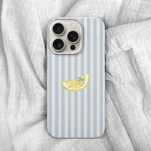 May include: A smartphone case with a light blue and white striped pattern. The case features a yellow lemon slice with a blue bow. The phone case has a camera module with three lenses.