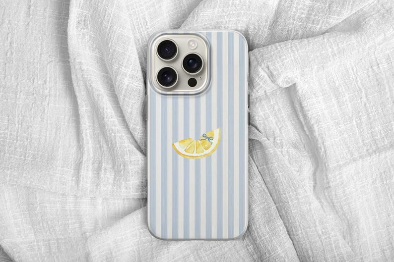May include: A smartphone case with a light blue and white striped pattern. The case features a yellow lemon slice with a blue bow. The phone case has a camera module with three lenses.