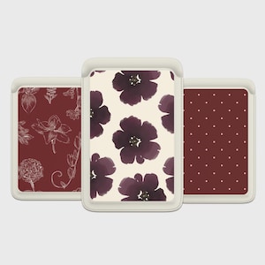 May include: Three card holders with floral patterns. The central holder displays large, dark purple flowers on a cream backdrop. The left holder has white floral line art on a burgundy background. The right holder has white polka dots on a burgundy background.