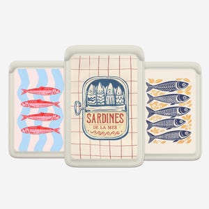 May include: Three decorative card holders with fish designs. One features red fish on blue and white stripes. Another shows a sardine can with the text "Sardines de la Mer". The third has blue fish with yellow accents.