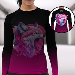 May include: Black and pink long-sleeve shirt featuring a vibrant illustration of a snarling fox. The design showcases a pink fox with blue eyes against a pink and purple background. The sleeves transition from black to pink.