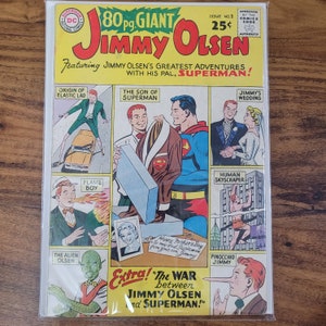 May include: A vintage comic book cover featuring Jimmy Olsen and Superman. The cover is red, white, and blue with a large image of Jimmy Olsen and Superman. The title of the comic is "Jimmy Olsen" and the subtitle is "Featuring Jimmy Olsen's Greatest Adventures with His Pal, Superman!" The cover also features a variety of smaller images of Jimmy Olsen in different situations, including him as a flame boy, an alien, and a human skyscraper.