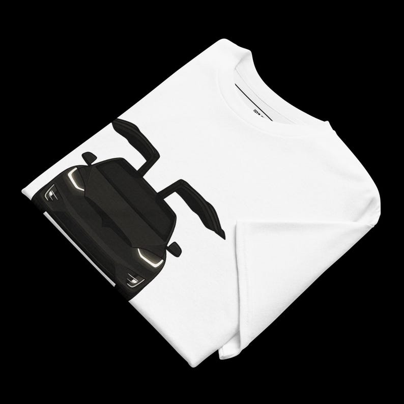 May include: White t-shirt featuring a black illustration of a sports car with its doors open. The car has bright headlights and a sleek design. The shirt is folded, showing the graphic on the front.