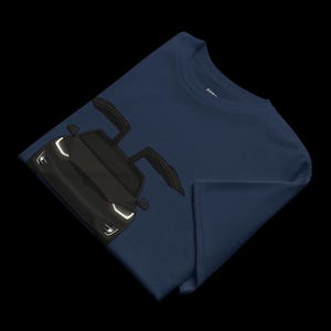 May include: Navy blue t-shirt featuring a black car with open doors. The car has white headlights and a sleek design. The t-shirt is folded, showcasing the car graphic prominently.