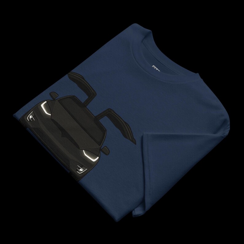 May include: Navy blue t-shirt featuring a black car with open doors. The car has white headlights and a sleek design. The t-shirt is folded, showcasing the car graphic prominently.