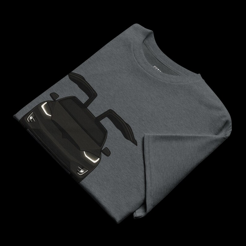 May include: Dark gray t-shirt featuring a black sports car graphic with open doors. The car's headlights are white. The t-shirt is folded, showing the front of the car and part of the shirt's sleeve.