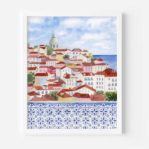 May include: Watercolor print of a European cityscape with red-tiled roofs, white buildings, and a domed structure. The image features a blue and white patterned border at the bottom, with a blue sky and ocean in the background. The artwork is framed in a white border.