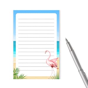 May include: A lined notepad with a beach scene and a pink flamingo. The notepad has a blue sky, white clouds, and a sandy beach with palm trees.