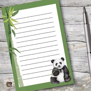 May include: Green and white lined notepad with a panda bear illustration holding a bamboo stalk. The panda is black and white and has a green bamboo stalk in its mouth. The background is green with a bamboo stalk and leaves.