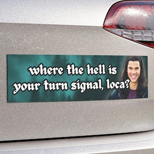 May include: A green and blue car bumper sticker with a photo of a young man with brown hair and a white shirt. The sticker says "where the hell is your turn signal, loca?"