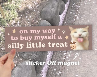 May include: A brown sticker or magnet with a white cat with a pink tongue sticking out. The text on the sticker reads "* on my way to buy myself a * silly little treat".