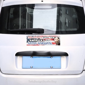 Puede incluir: Un coche blanco con una pegatina en el parachoques que dice "True Patriots Brake for America's Only Native Marsupial". La pegatina presenta una bandera estadounidense y una imagen de una zarig&uuml;eya.