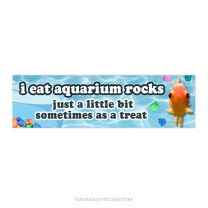Könnte beinhalten: Ein blaues und weißes Banner mit einem Goldfisch und bunten Steinen. Auf dem Banner steht "i eat aquarium rocks just a little bit sometimes as a treat".