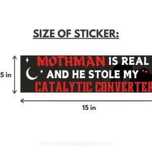 May include: A rectangular bumper sticker with a black background featuring the red and white text MOTHMAN IS REAL AND HE STOLE MY CATALYTIC CONVERTER. The design includes a white crescent moon, stars, and a dark silhouette with glowing red eyes. It measures 38.1 cm by 9.53 cm.