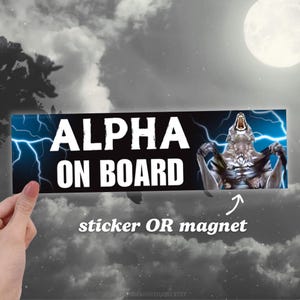 Puede incluir: Una pegatina o imán negro y azul con un lobo blanco aullando a la luna. El texto "ALPHA ON BOARD" está escrito en letras blancas sobre un fondo negro. El lobo está rodeado de rayos.