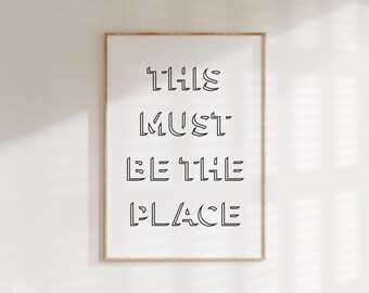 May include: A framed print with the text "THIS MUST BE THE PLACE" in a bold, outlined font.