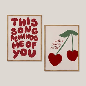 May include: Two framed prints with a pink background. The first print has red text that says "This song reminds me of you". The second print has a green stem with two red cherries and the text "with a cherry on top".