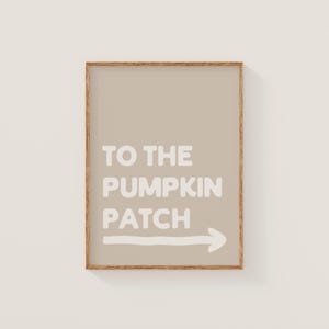 Puede incluir: Una impresión enmarcada con un fondo beige y las palabras "TO THE PUMPKIN PATCH" en blanco, con una flecha blanca que apunta hacia la derecha. El marco es de color marrón claro.