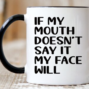 May include: White ceramic coffee mug with a black handle. The mug has black text that reads "If my mouth doesn't say it my face will."