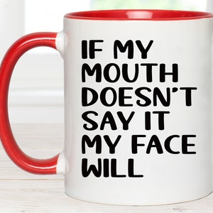 May include: White ceramic coffee mug with a red rim and handle. The mug has black text that reads "If my mouth doesn't say it my face will."
