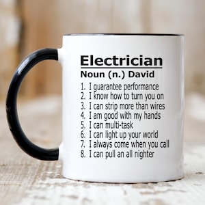 May include: White ceramic mug with a black handle and rim. The mug features the word "Electrician" in bold black letters, followed by "Noun (n.) David" and a list of eight statements about an electrician's skills and abilities.