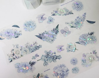 Puede incluir: Una hoja de pegatinas florales azules iridiscentes con el texto "Dusty Blue Flowers" y "Byumee".
