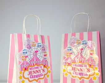 Könnte beinhalten: Zwei Geschenktüten aus Papier mit weißen und rosa vertikalen Streifen und weißen gedrehten Papiergriffen. Jede Tüte zeigt eine zentrale Grafik eines Riesenrads, Zelten und Feuerwerk mit dem Text "WELCOME TO JENNY'S CARNIVAL".