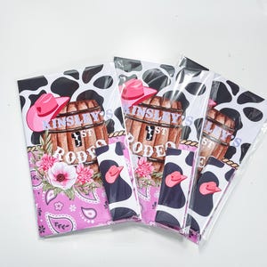 Puede incluir: Cuatro bolsas de regalo de fiesta de estampado de vaca rosa y negro con un diseño de bandana rosa y el texto "Kinsley's 1st Rodeo" y "Lily's 1st Rodeo".