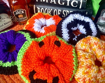 Può includere: Un set di sei scrunchies per capelli in maglia a tema Halloween. Gli scrunchies sono di vari colori, tra cui arancione, nero, bianco, verde e giallo. Gli scrunchies sono decorati con un viso di zucca, mais dolce e strisce bianche e nere.