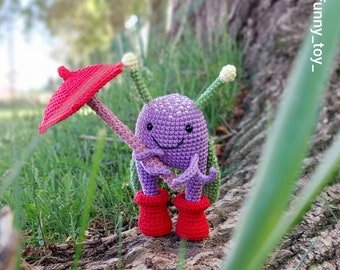 May include: A purple crocheted creature with a smiling face, wearing red rain boots and holding a red umbrella. The creature has long green and yellow stems and is sitting on a tree stump.
