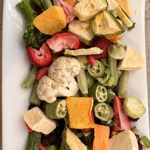 May include: A white plate filled with a variety of dried fruits and vegetables, including strawberries, broccoli, cauliflower, zucchini, and green beans.

“Premium freeze-dried bird food by Runzas made with real fruits and vegetables for parrots”
