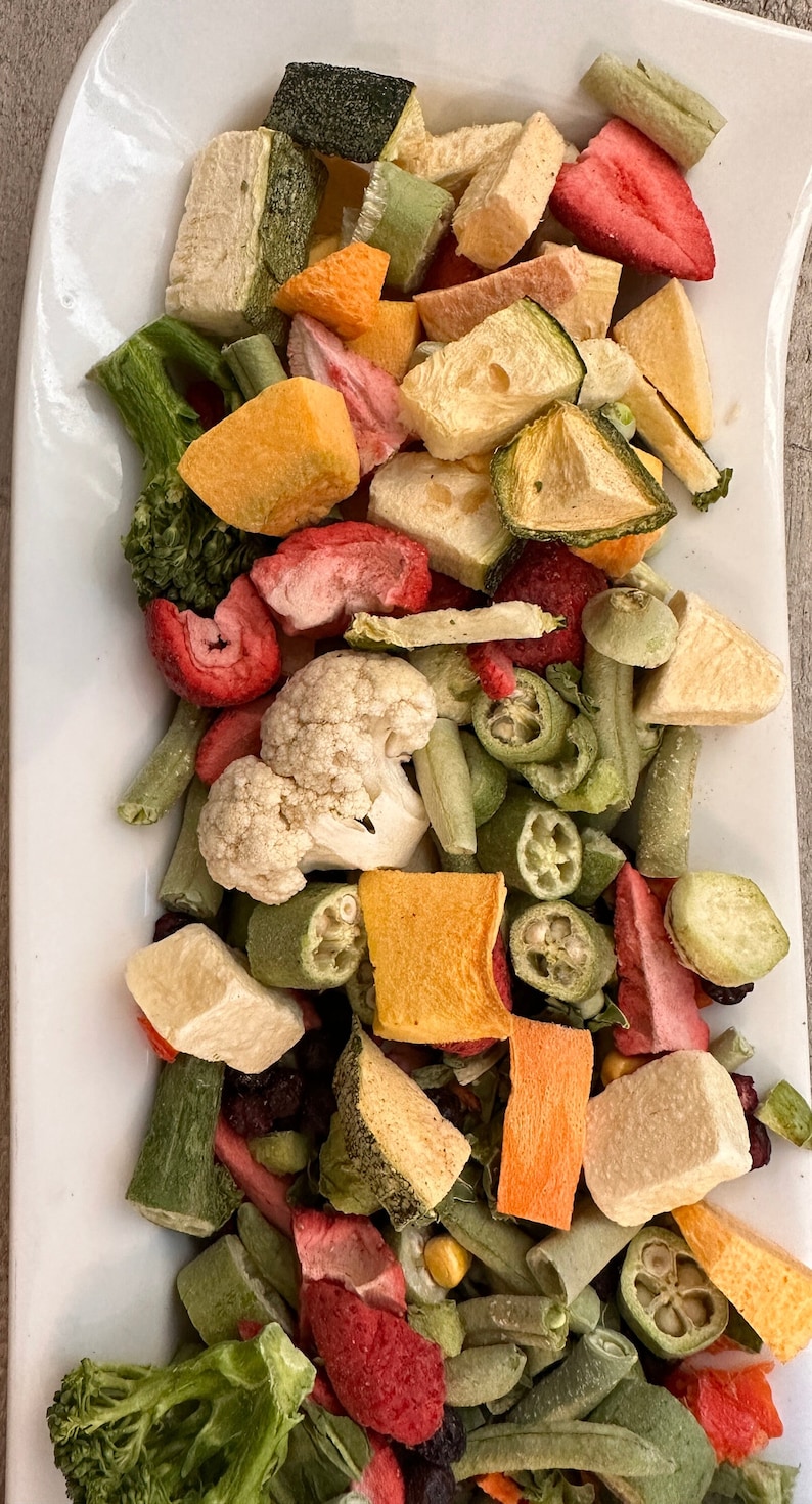 May include: A white plate filled with a variety of dried fruits and vegetables, including strawberries, broccoli, cauliflower, zucchini, and green beans.

“Premium freeze-dried bird food by Runzas made with real fruits and vegetables for parrots”
